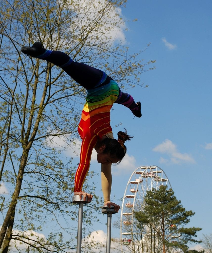 Photo of a circus performer doing handstand on stilts with full side splits.